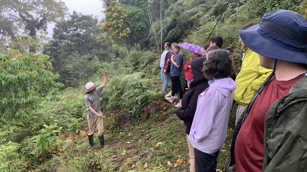 A faculty member and students listening to a local farmer on a mountain, demonstrating experiential learning abroad.
